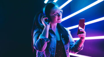 Sillhoutte of hip-hop girl with headphones at the neon light. Fashion portrait of modern young woman making selfie.