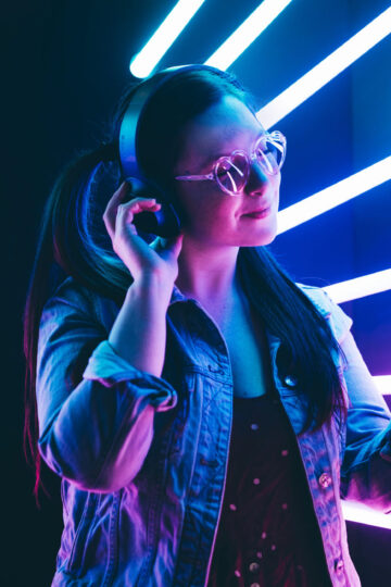 Sillhoutte of hip-hop girl with headphones at the neon light. Fashion portrait of modern young woman making selfie.