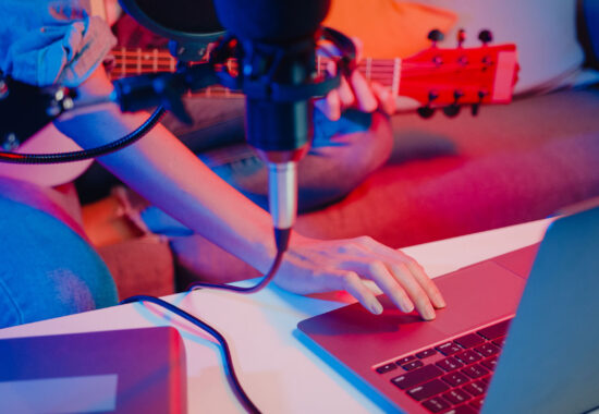 Happy asia girl blogger play guitar and use microphone sing song record music sound mixer on laptop in modern living room home studio at night. Music content creator, Tutorial, Broadcast concept.